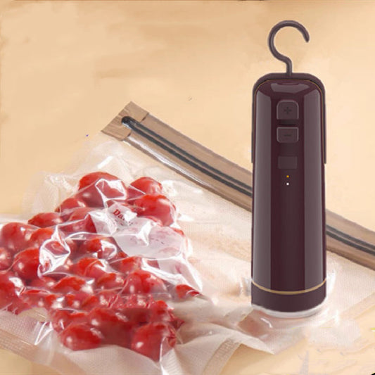 Compact handheld electric vacuum sealer being used on a reusable textured storage bag for sous vide cooking preparation.