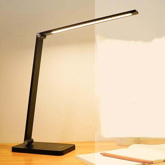 Modern black LED desk lamp with a smartphone charging wirelessly on its base and a flexible neck for eye-care study lighting.
